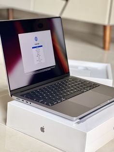 an open laptop computer sitting on top of a white box