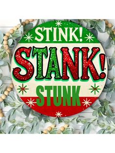 a sign that says stink stank stuk surrounded by green leaves and wooden beads