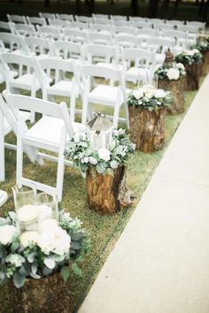 chairs lined up on the grass with white flowers and greenery