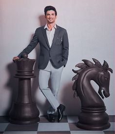 a man standing next to two giant chess pieces