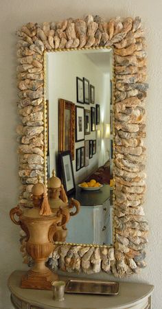 a mirror sitting on top of a table next to a vase filled with flowers and seashells