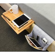 a table with a laptop, tablet and cell phone on it next to a bed