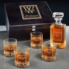 four whiskey glasses and a decante bottle in front of a box with the name william's on it