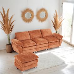 an orange couch and ottoman in a white living room with two mirrors on the wall