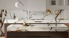 a modern kitchen with marble counter tops and white cabinets, along with hanging lights above the sink