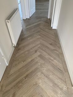 an empty hallway with wood flooring and white trim on the walls, along with two radiators