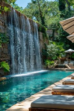 an outdoor pool with waterfall and lounge chairs