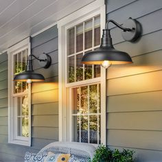 two lights on the side of a house next to a bench and potted plant