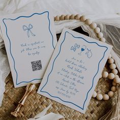 two white cards with blue writing on them next to a beaded necklace and tassel