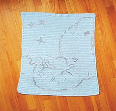 a crocheted blanket on the floor with a cat drawn on it's back