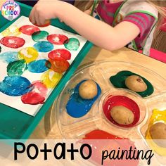 a child is painting with colorful paints on a paper and plastic tray that sits on the table