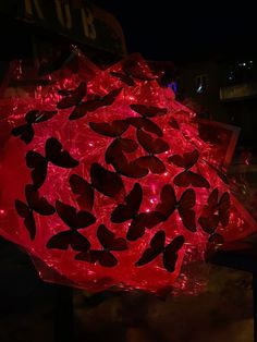 a red umbrella that has some black butterflies on it and is lit up at night