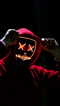 a person in a red hoodie holding up a mask with the light on it