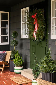 the front porch is decorated for christmas with wreaths and potted plants