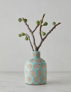 a vase with some branches in it on a white counter top and a wall behind it