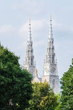 two spires on top of a building with trees in the foreground