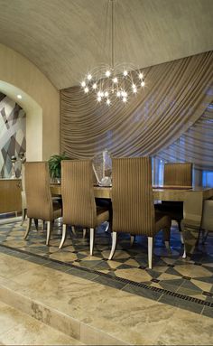 a dining room table with chairs and a chandelier hanging from it's ceiling