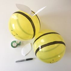 two large yellow balloons sitting on top of a white table next to scissors and tape