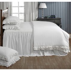 a bed with white ruffled bedspread and pillows