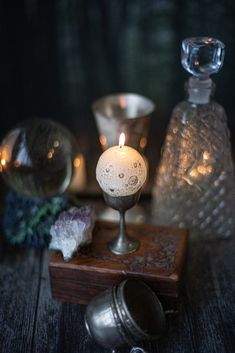 a candle sitting on top of a wooden table next to some glass bottles and candles