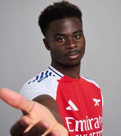 a young man in a red and white shirt pointing at the camera with his finger