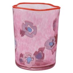 a pink glass vase with blue and red flowers on it's rim, against a white background