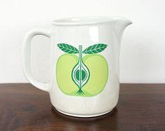 a white pitcher with an apple on it