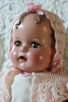 an old fashioned baby doll wearing a pink bonnet