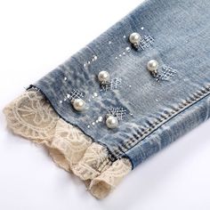 an old pair of jeans with pearls and lace on them are sitting on a white surface