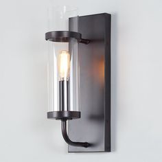 a light that is on the wall next to a glass lamp shade and black metal frame