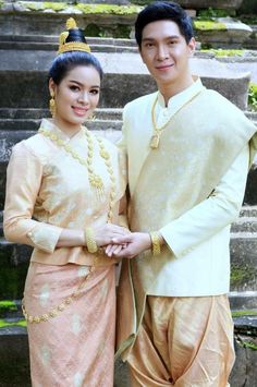 a man and woman standing next to each other in front of some steps with their hands together