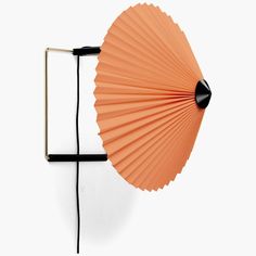 an orange fan is hanging on the wall next to a black and gold lamp holder