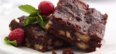 two pieces of chocolate brownie with raspberries on the side