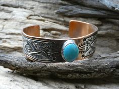 This is a beautiful Handcrafted Native American Navajo Made bracelet cuff. This is a wider cuff/bracelet about 3/4 inch width and is accented with a Turquoise Cabochon Gemstone. It is handcrafted with Copper and has a Hand Stamped Sterling Silver 925 designed Overlay.  There is also hand stamping on the copper part of the bracelet to give it a beautiful finished design. This Item is handcrafted here in the USA and is Hallmarked by the Artist. The cuff is entirely Handcrafted which makes it a ONE Western Style Cuff Jewelry For Gift, Stamped Turquoise Bracelet As Gift, Southwestern Blue Cuff Bracelet As Gift, Western Style Engraved Bracelets For Gifts, Stamped Turquoise Cuff Bracelet Gift, Artisan Bracelet With Concho As Gift, Turquoise Stamped Cuff Bracelet As Gift, Artisan Concho Bracelets For Gift, Artisan Concho Bracelet For Gift