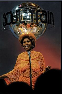 a woman standing in front of a microphone and disco ball on top of her head