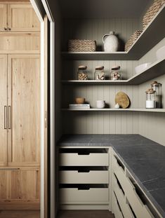 a kitchen with open shelving and wooden cabinets in the back wall, along with black counter tops