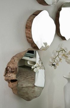 three mirrors mounted to the side of a wall next to a vase with flowers on it