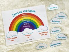 the days of the week with clouds and rainbows on a fluffy white surface next to it