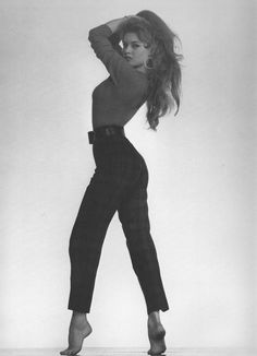 a black and white photo of a woman with her hair in the air, wearing high heels