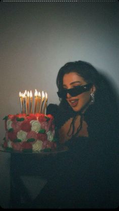 a woman in black holding a cake with candles on it