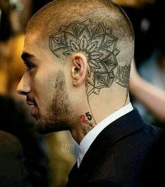 a man with a tattoo on his head looking to the side and wearing a suit