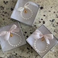 three personalized bracelets in clear boxes with ribbon and bow on the top one