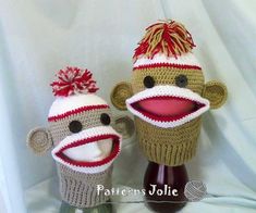 two crocheted socky hats with red and white pompoms on them