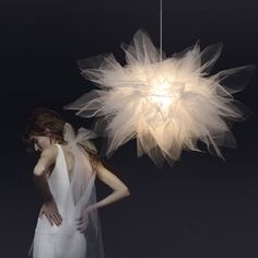 a woman in a white dress standing next to a light that looks like a flower