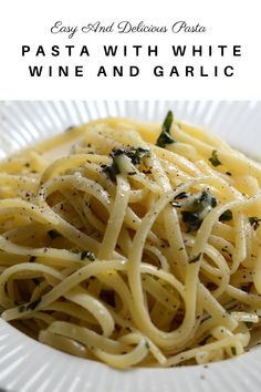 a white plate topped with pasta covered in parmesan cheese and spinach leaves