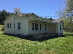 a small white house sitting on top of a lush green field