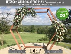 a wooden arch decorated with flowers and greenery in the middle of a grassy field