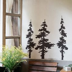 a bench sitting in front of a window next to a wall with trees on it