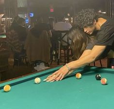 a man and woman leaning over a pool table