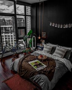 a bedroom with black walls, wooden floors and a large window that overlooks the city